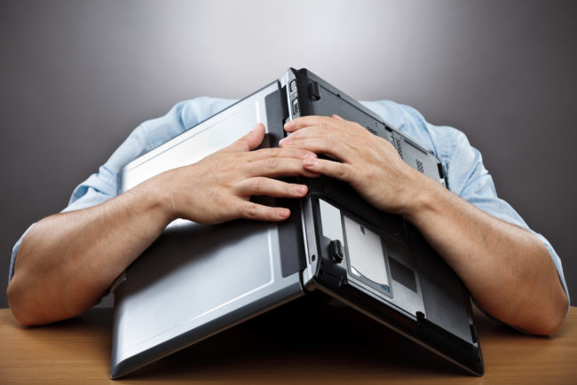 Interest Rates Are Rising - man hiding head under laptop - deposit photos